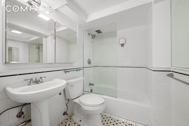 bathroom featuring visible vents, shower / bath combination, toilet, and tile walls