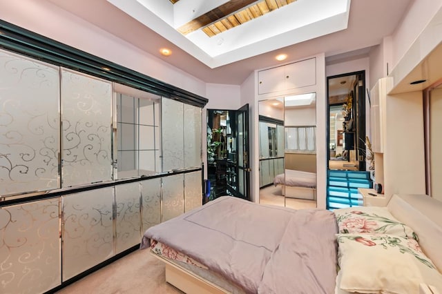 bedroom with a skylight, a raised ceiling, and light colored carpet