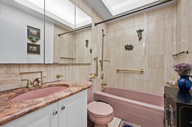 bathroom with tile walls, shower / bathtub combination, tasteful backsplash, toilet, and vanity