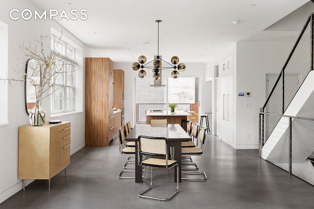 dining area featuring a chandelier, stairway, and baseboards