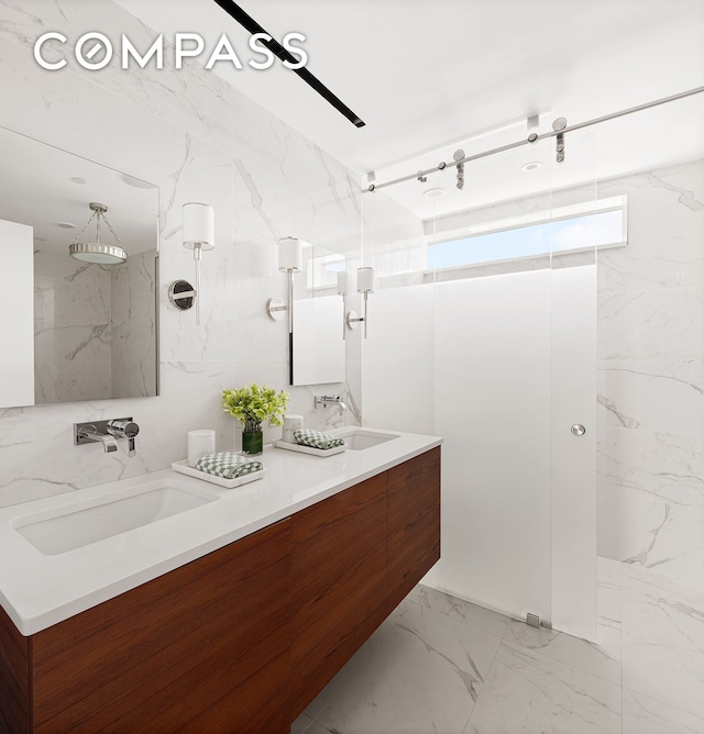 bathroom with a marble finish shower, marble finish floor, double vanity, and a sink