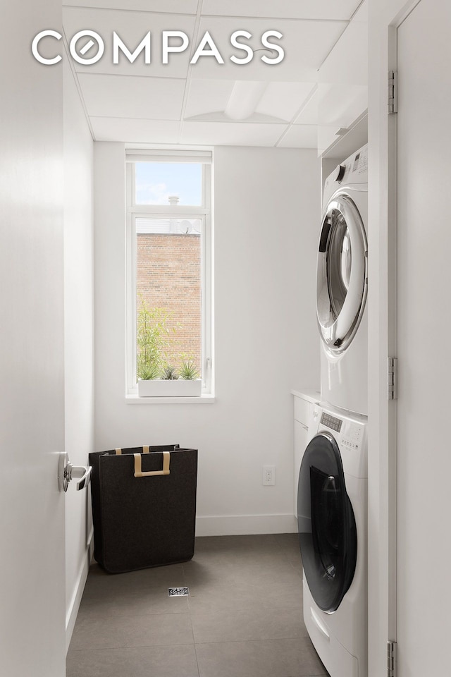 laundry area with laundry area, stacked washing maching and dryer, and baseboards