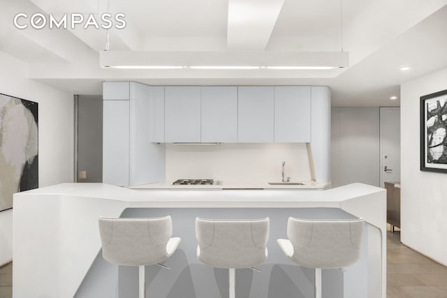 kitchen featuring a sink, white cabinetry, light countertops, a tray ceiling, and modern cabinets