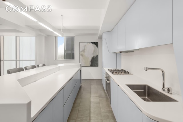 kitchen featuring stainless steel appliances, light countertops, white cabinetry, a sink, and modern cabinets