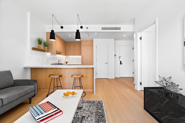 kitchen featuring visible vents, a peninsula, light countertops, a kitchen bar, and pendant lighting