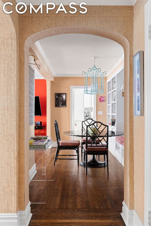 dining area with ornamental molding, hardwood / wood-style floors, and an inviting chandelier