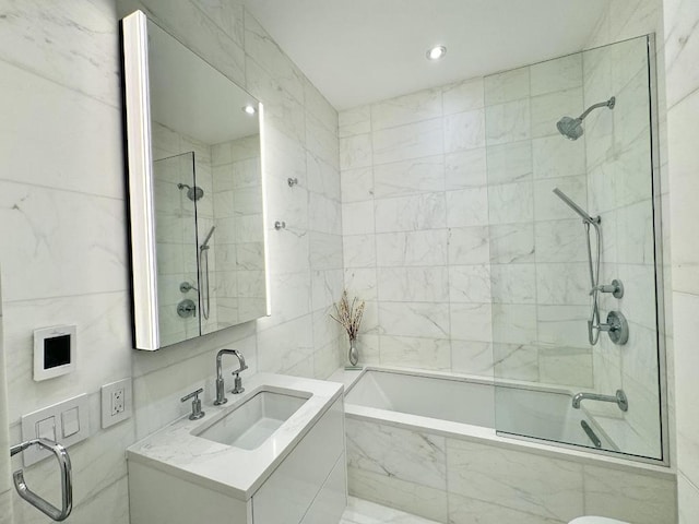 bathroom featuring vanity, tiled shower / bath combo, and tile walls