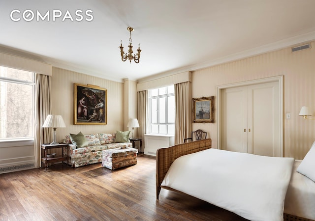 bedroom featuring visible vents, wood finished floors, crown molding, and a chandelier