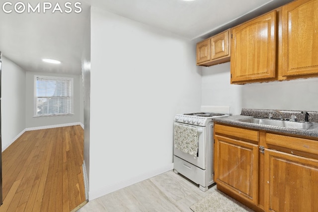 kitchen featuring white electric range oven, sink, and light hardwood / wood-style flooring