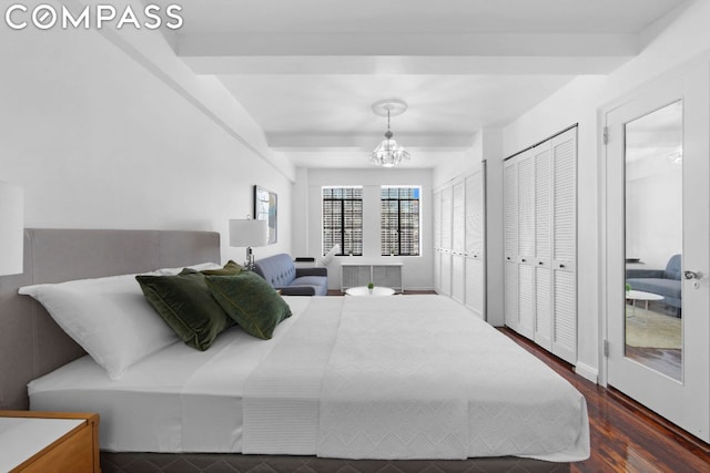 bedroom featuring dark wood-type flooring, multiple closets, radiator heating unit, a notable chandelier, and beamed ceiling