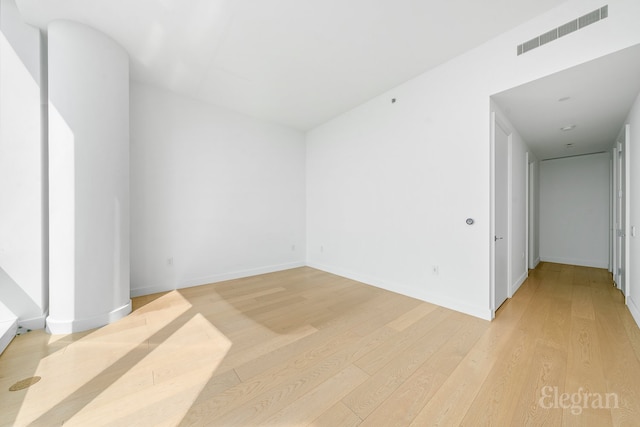 spare room with light wood-style floors, visible vents, and baseboards