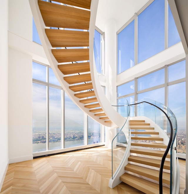 stairs with a water view, a towering ceiling, and baseboards