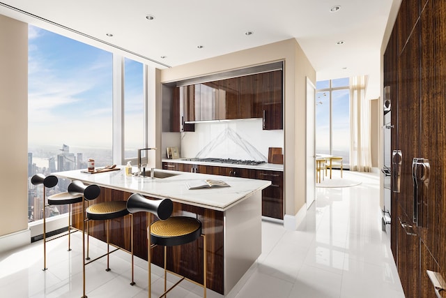 kitchen featuring modern cabinets, stainless steel gas stovetop, a kitchen island with sink, a kitchen bar, and a sink