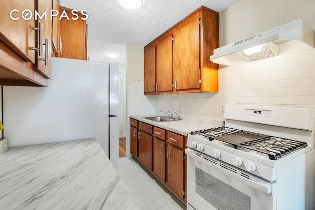 kitchen with tasteful backsplash, sink, a textured ceiling, and white appliances