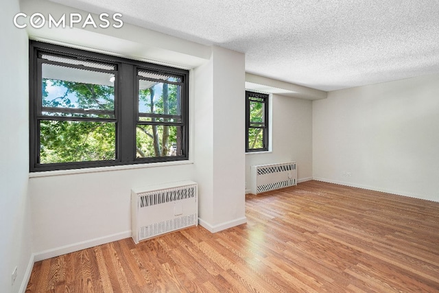 empty room with radiator, light hardwood / wood-style floors, and a textured ceiling