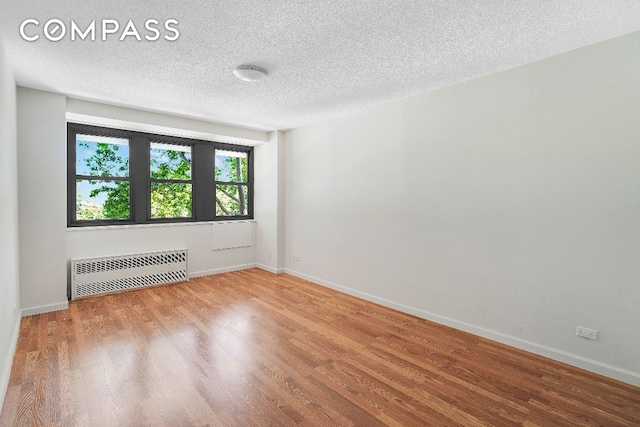 unfurnished room featuring radiator heating unit, wood-type flooring, and a textured ceiling