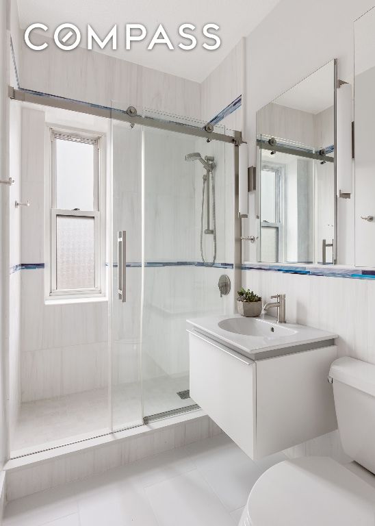 bathroom with walk in shower, vanity, and toilet