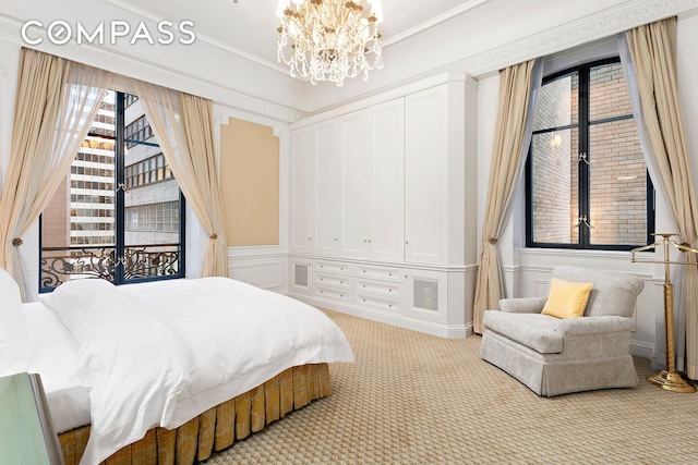 carpeted bedroom featuring a chandelier, ornamental molding, and a decorative wall