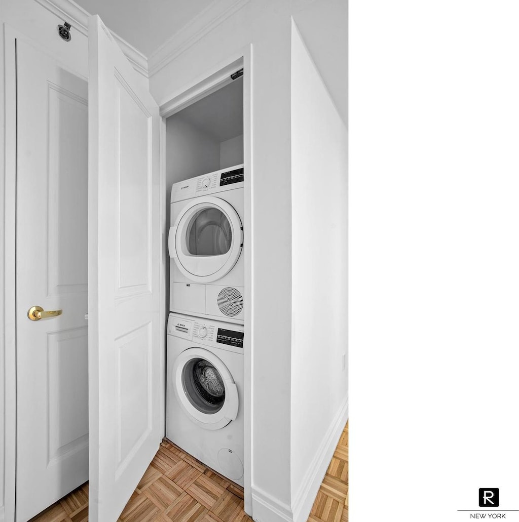 clothes washing area featuring stacked washer and clothes dryer and crown molding