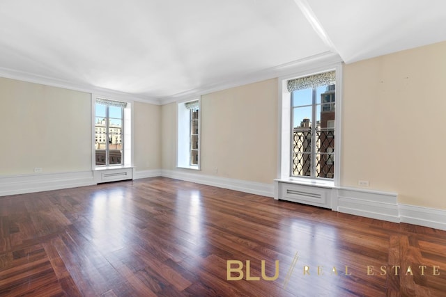 spare room with wood finished floors, baseboards, and ornamental molding