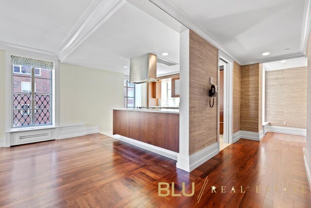 interior space featuring kitchen peninsula, crown molding, and hardwood / wood-style floors