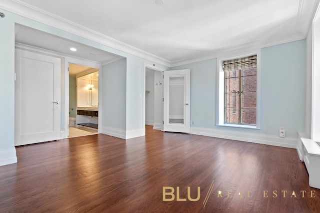 spare room with ornamental molding, baseboards, and wood finished floors