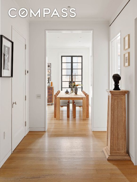 hall featuring ornamental molding, baseboards, and light wood finished floors