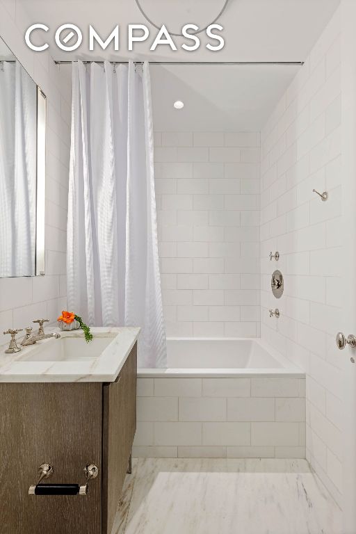 bathroom with marble finish floor, tiled shower / bath combo, and vanity