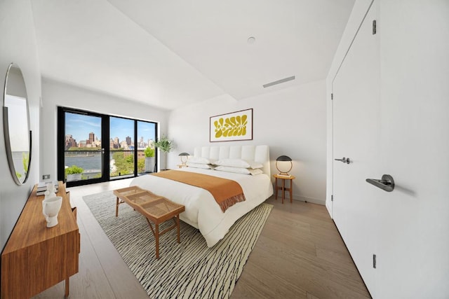 bedroom with a water view and hardwood / wood-style flooring