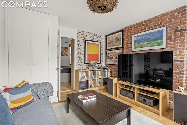 living room with brick wall and wood-type flooring