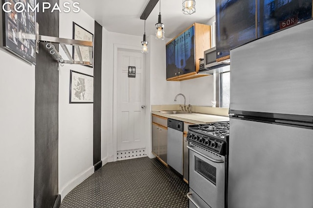 kitchen with baseboards, a sink, light countertops, appliances with stainless steel finishes, and pendant lighting