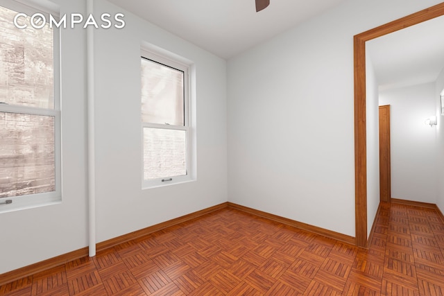 empty room with ceiling fan and baseboards