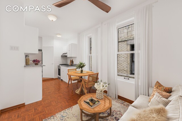 living room with dark parquet floors and ceiling fan