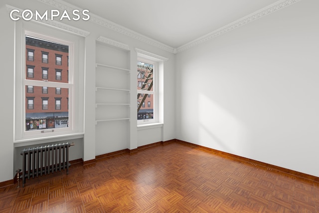 unfurnished room featuring radiator, baseboards, ornamental molding, and built in shelves