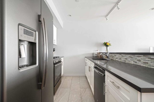 30-25 21st St Unit 2-A, New York City, NY 11102 - kitchen with appliances with stainless steel finishes, a sink, rail lighting, dark countertops, and white cabinetry