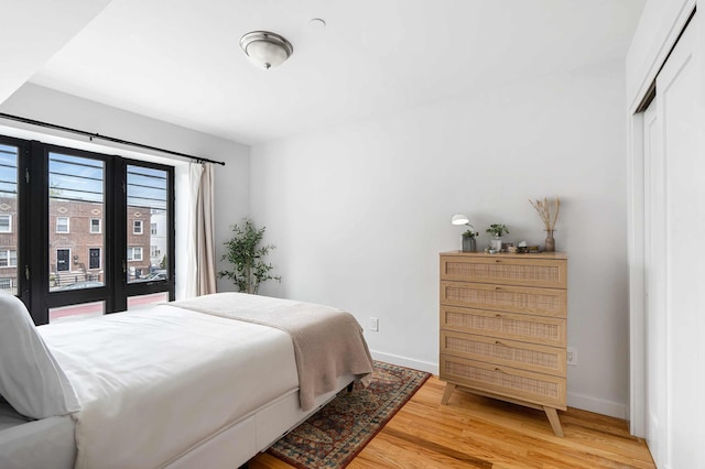 30-25 21st St Unit 2-A, New York City, NY 11102 - bedroom with light wood-style flooring, baseboards, and a closet