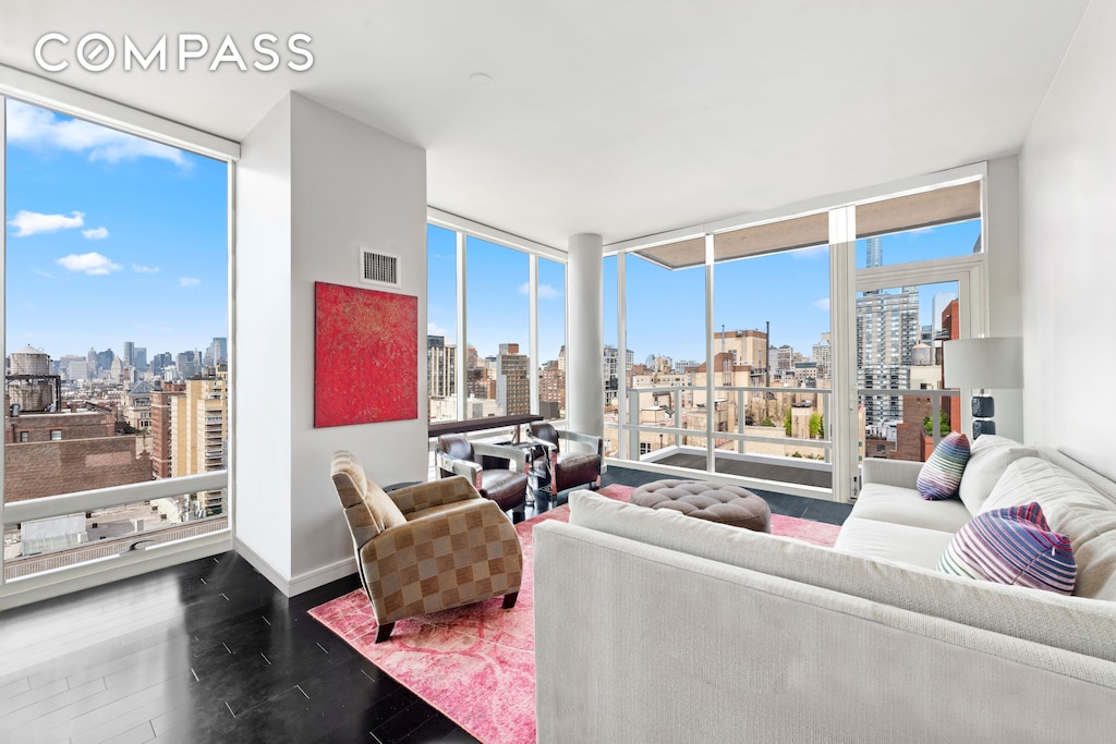 living room featuring expansive windows, a view of city, and a healthy amount of sunlight