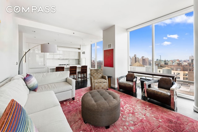 living room featuring a view of city, wood finished floors, visible vents, and expansive windows