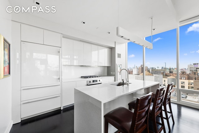 kitchen featuring expansive windows, a sink, white cabinets, a view of city, and modern cabinets