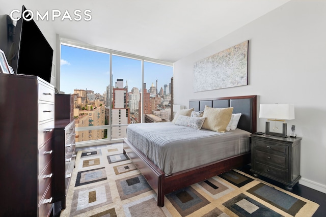 bedroom featuring baseboards, floor to ceiling windows, and a city view