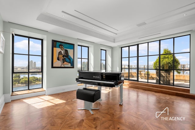 sitting room with ornamental molding, a raised ceiling, a city view, and baseboards