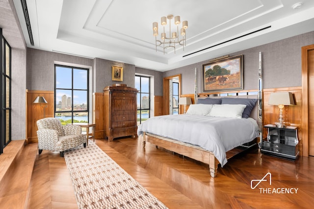 bedroom with a chandelier, a raised ceiling, and wallpapered walls