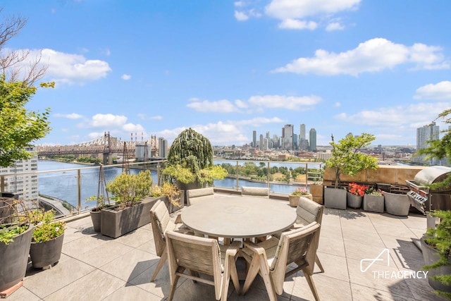 view of patio / terrace with a view of city, a water view, and outdoor dining space