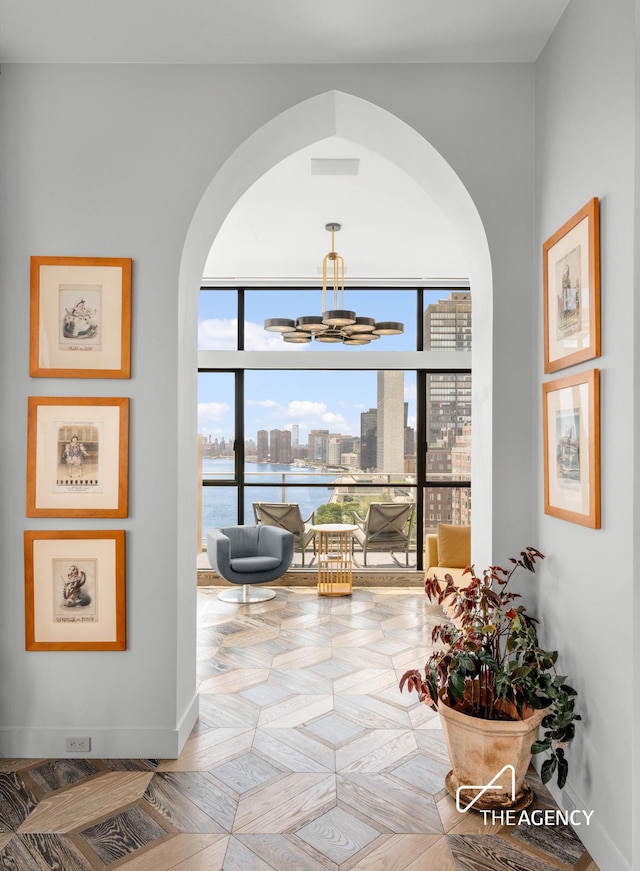 sitting room with a view of city, an inviting chandelier, and baseboards