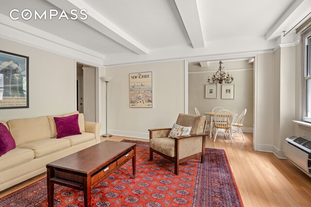 living room with light wood-type flooring, a chandelier, a wall mounted AC, and beam ceiling