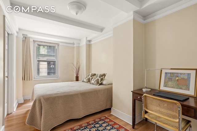 bedroom with baseboards, beam ceiling, and wood finished floors