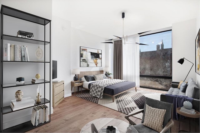 bedroom with baseboards, floor to ceiling windows, and wood finished floors