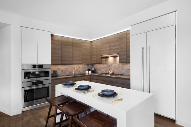 kitchen with sink, appliances with stainless steel finishes, backsplash, a center island, and white cabinets