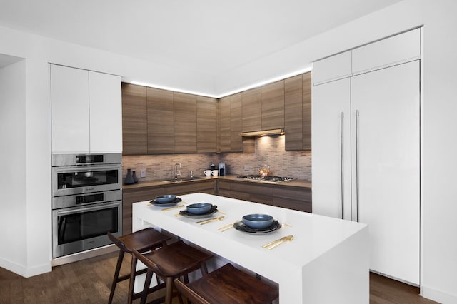 kitchen with stainless steel appliances, white cabinetry, a kitchen island, a sink, and modern cabinets