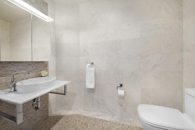 bathroom with toilet, decorative backsplash, tile walls, and sink